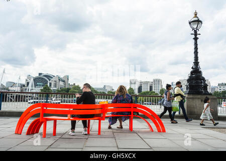 Un couple assis sur l'un de par la modification de Jeppe Hein Bancs sociaux sur London's South Bank, SE1, UK Banque D'Images