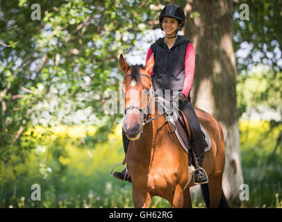 Jeune femme sur une promenade à cheval dans une forêt Banque D'Images