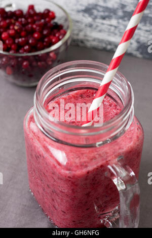 Smoothie canneberge en pot Mason avec une paille sur un fond de bois Banque D'Images