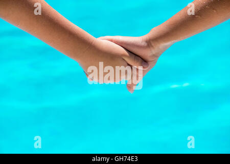 Deux jeunes personnes se tenant la main heureuse en face d'une piscine bleu clair. prix pour le texte et l'espace de copie Banque D'Images