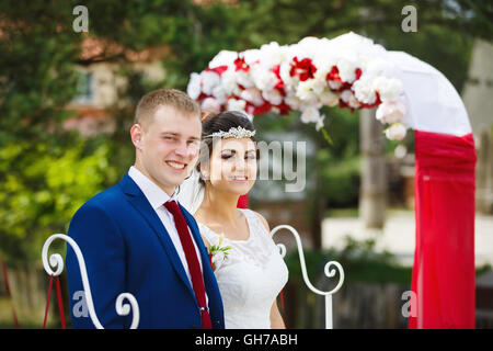 Couple de mariage contre l'arc rouge à l'enregistrement de mariage Banque D'Images