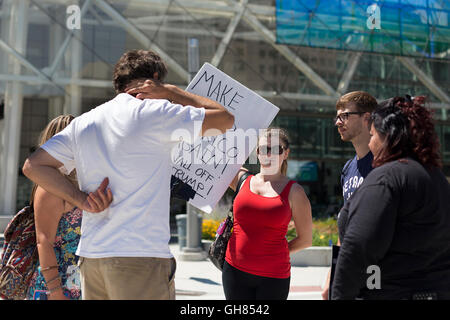 Detroit, USA. Le 08 août, 2016. Anti-Trump protestataire Colette Mariage, 32, de Harrison, MI. en rouge, se trouve dans un cercle de manifestants à l'extérieur du Cobo Hall au centre-ville de Detroit le lundi 8 août 2016 alors que le candidat républicain Donald Trump a parlé à l'Economic Club. La grande foule de manifestants a diminué rapidement après avoir fini de parler d'Atout. ·C'est une lutte contre le nationalisme et la xénophobie. Il·s juste la question d'humanité,· mariage dit qui va voter pour Hillary Clinton en novembre. Photo : Elaine Cromie/DPA dpa : Crédit photo alliance/Alamy Live News Banque D'Images