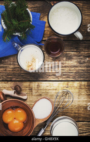 Ingrédients Lait de poule sur table en bois rustique (vue de dessus). Lait oeufs crus avec poinçon d'oeufs, lait, crème, sucre, bourbon Banque D'Images