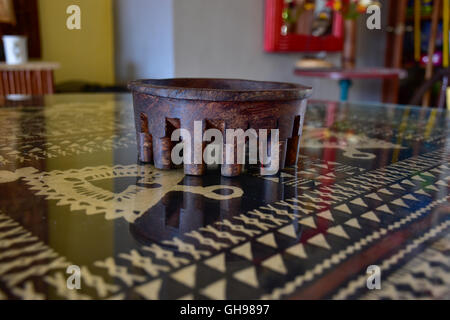 Tanoa Samoan antique ou laulau le kava bol sculpté dans du bois. Tapa Samoan chiffon sous verre sur table. Banque D'Images