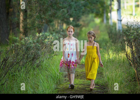 Deux petites filles promenade à travers le parc se tenant la main. Banque D'Images