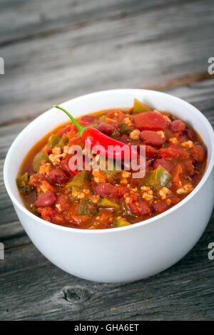 Chili con carne porc bol sur un fond texturé bois Banque D'Images