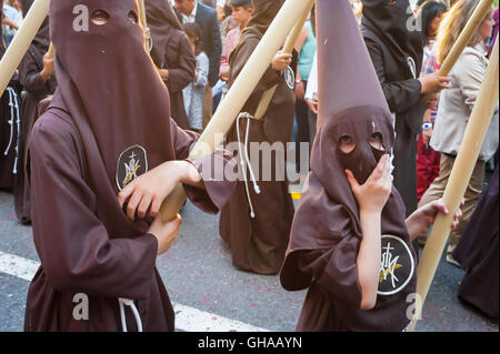 Séville Pâques Espagne, les jeunes membres d'un cofradia à capuche (fraternité) marchent dans une procession dans le festival de la semaine Sainte de Pâques à Séville, Espagne. Banque D'Images