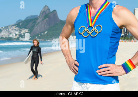 RIO DE JANEIRO - Mars 10, 2016 : l'athlète Gay se dresse sur la plage d'Ipanema portant des anneaux olympiques médaille d'or avec ruban arc-en-ciel. Banque D'Images