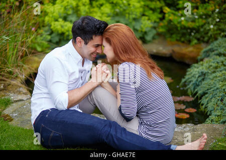 Couple d'amoureux assis dehors dans le jardin Banque D'Images