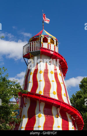 La colorée, structure élevée d'un helter skelter glisser à une fête foraine ou d'expositions dans le cadre d'un ciel bleu lumineux. Banque D'Images