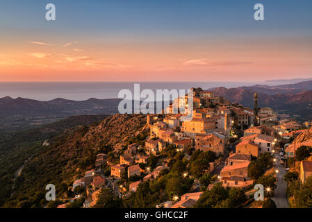 Le village de Balagne Speloncato en Corse au crépuscule baigné de soleil de fin de soirée avec des lampadaires sur le Regino valley et Banque D'Images