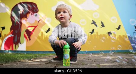 2 ans Carson Oisin joue avec bulles près d'une nouvelle fresque peinte par l'artiste graffiti Solus au Diamond Park de Dublin's Gardiner Street comme logements étudiants est construit dans la région. Banque D'Images