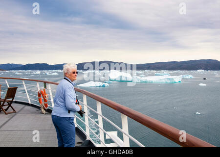 Les passagers touristiques supérieurs à la retraite sur l'extérieur de pont d'un bateau de croisière naviguant dans Bredefjord fjord avec des icebergs dans l'été. Narsaq Groenland Banque D'Images