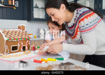 Mère et fille decorating gingerbread house Banque D'Images