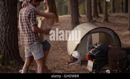 Young couple hugging extérieur tente dans woods Banque D'Images