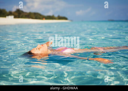 Serene woman floating in tropical ocean Banque D'Images