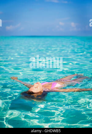 Serene woman floating in tropical ocean Banque D'Images