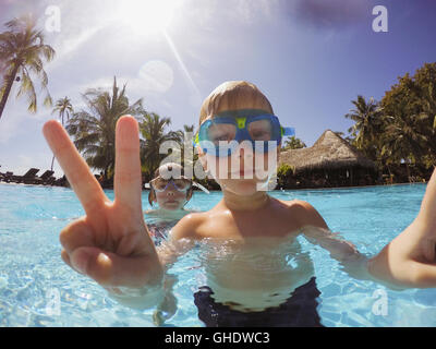 Portrait of boy gesturing signe de paix en piscine tropicale Banque D'Images