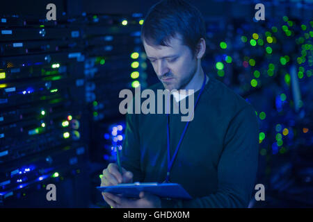 Technicien Salle serveur en prenant des notes sur le presse-papiers Banque D'Images