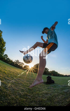 Un garçon jouant au football, l'exécution de freestyle dans un parc urbain à jouer Banque D'Images