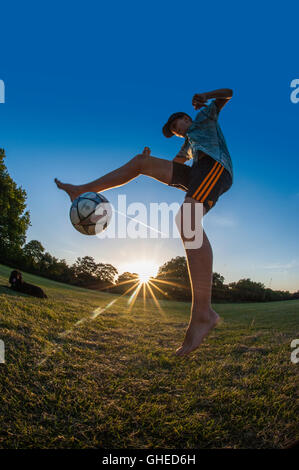 Un garçon jouant au football, l'exécution de freestyle dans un parc urbain à jouer Banque D'Images