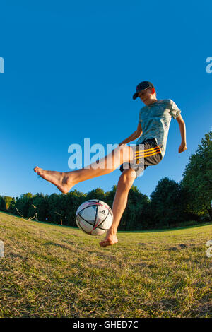 Un garçon jouant au football, l'exécution de freestyle dans un parc urbain à jouer Banque D'Images