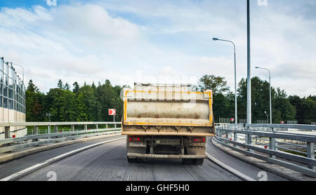 Gros camion benne industrielle va sur route asphaltée, vue arrière Banque D'Images