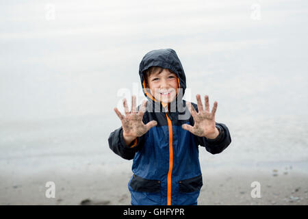 Garçon profitant de la pluie et de s'amuser à l'extérieur sur la plage une pluie gris Banque D'Images