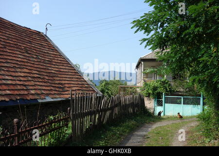 Haghbat village au nord de l'Arménie maisons traditionnelles lane metal gate poulets clôture en bois toit de tuiles montagnes au loin Banque D'Images