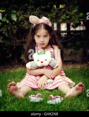 Portrait of Little Girl sitting on grass,holding soft toy Banque D'Images