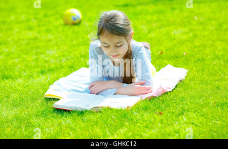 Girl reading book on Green grass Banque D'Images