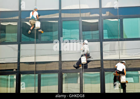 Un groupe de trois personnes nettoyer les fenêtres alors qu'à une corde Banque D'Images