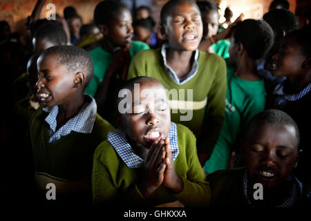 Les enfants de l'école africaine en Ouganda rural prendre un moment au cours de l'Assemblée à la prière du matin au matin chapelle Banque D'Images