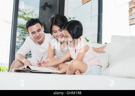 Bénéficiant de l'enfant avec les parents de coloriage à la maison. Banque D'Images