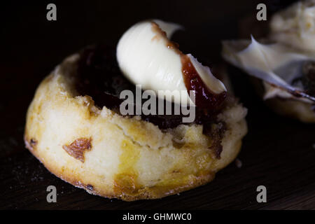 Un scone de fruits servis avec de la crème caillée et confiture de framboises dans le cadre de thé de l'après-midi. Banque D'Images