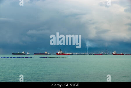 Vue sur le détroit de Singapour à partir de l'île de Sentosa. Les navires, les paysages industriels et de mauvais temps. Banque D'Images