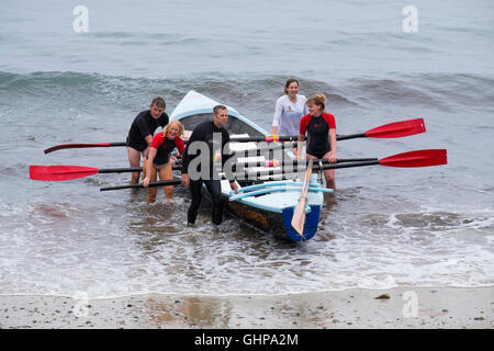 Une équipe d'aviron avec un concert en bateau sur la plage de Trevaunance Cove, St Agnes, Cornwall, England, UK Banque D'Images