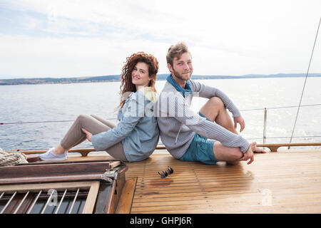 Jeune couple on yacht assis dos à dos Banque D'Images