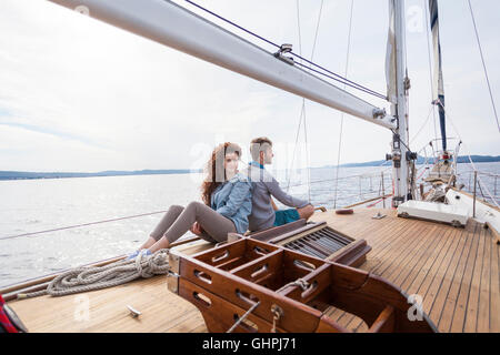 Jeune couple on yacht assis dos à dos Banque D'Images