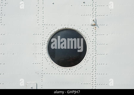 Photographié close-up de revêtement métallique et hublot en avion militaire en gris Banque D'Images