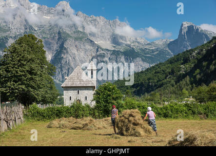 Recherche à travers le village de Theth avec son église au toit de bardeaux et les Alpes en arrière-plan, le nord de l'Albanie. Banque D'Images