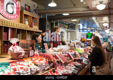 Seattle, Washington : Tracy donne un exemple d'un client à l'Chukar cerises au Pike Place Market. Banque D'Images