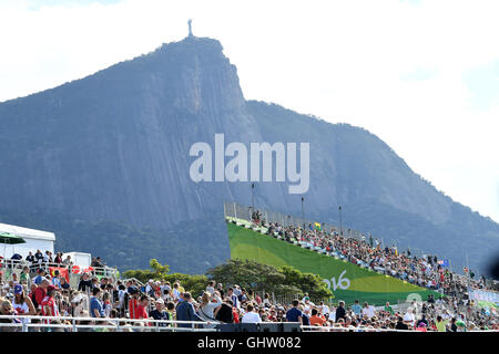 Rio de Janeiro, Brésil. Août 11, 2016. Sur les stands sous la statue du Christ Rédempteur spectateurs regarder les compétitions d'aviron des Jeux Olympiques de Rio 2016 à Lagoa Stadium à Rio de Janeiro, Brésil, le 11 août 2016. Photo : Soeren Stache/dpa/Alamy Live News Banque D'Images