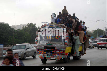 Les passagers voyagent sur le toit d'un bus surchargé en raison du manque de transports, comme l'Association CNG All-Pakistan a annoncé la fermeture de toutes les stations de GNC dans le Sindh pour une période indéfinie en protestation contre le despotisme et les menaces lancées par un haut fonctionnaire de l'autorité de réglementation du pétrole et du gaz (OGRA), à Karachi le Jeudi, août 11, 2016. Banque D'Images