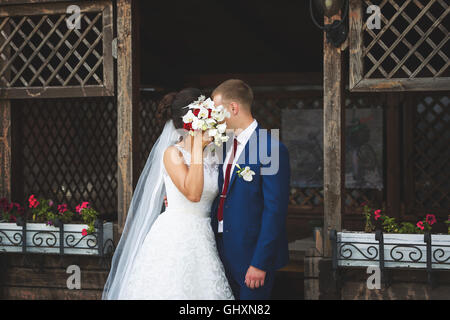 Se cacher derrière le couple de mariage bouquet de mariée dans une maison de jardin en bois Banque D'Images