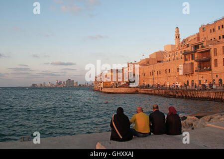 Israël : une famille musulmane assis au port de Jaffa avec vue sur la vieille ville au coucher du soleil Banque D'Images