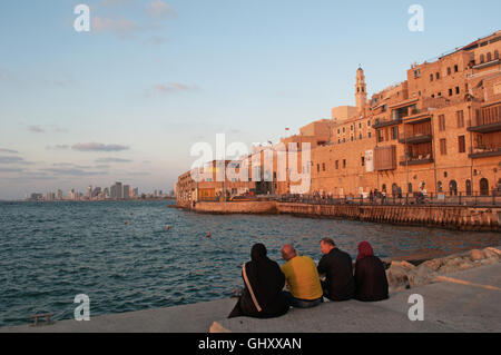 Israël : une famille musulmane assis au port de Jaffa avec vue sur la vieille ville au coucher du soleil Banque D'Images