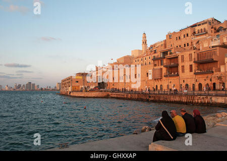 Israël : une famille musulmane assis au port de Jaffa avec vue sur la vieille ville au coucher du soleil Banque D'Images