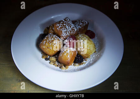 Un sucre saupoudré dessert servi à Terre-Neuve et Labrador, Canada. Fruits frais de saison est servi avec la pâte frite. Banque D'Images
