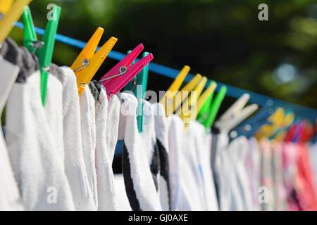 Le séchage des vêtements pendus sur la corde en la fixant avec des pinces à linge de couleur. Banque D'Images